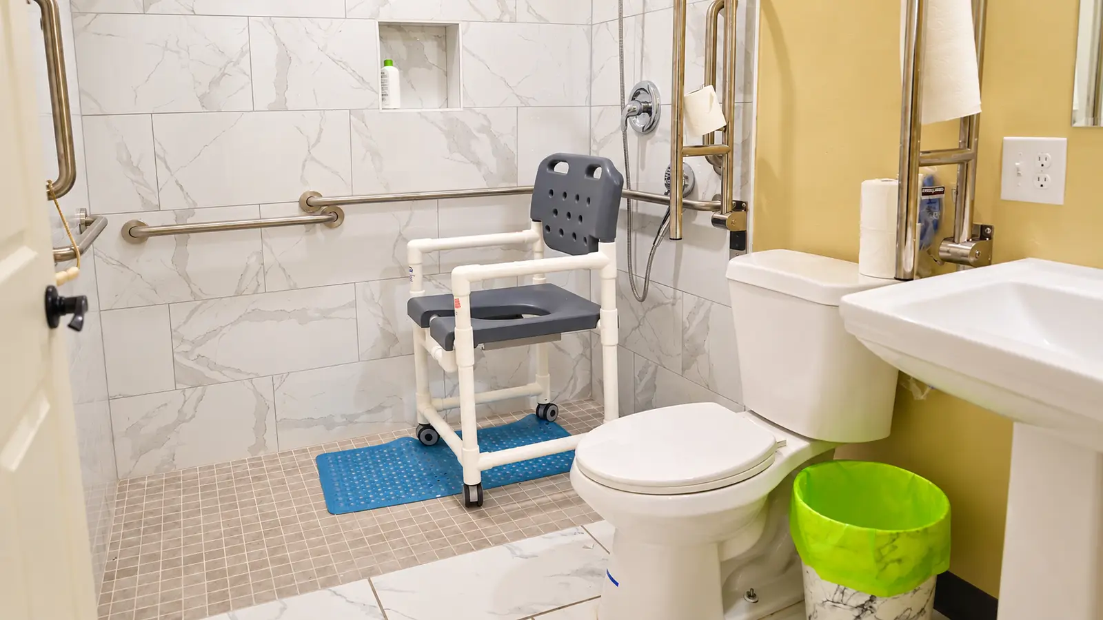 A tiled roll-in shower and shower chair at Prime Adult Family Home, with grab bars along the wall
