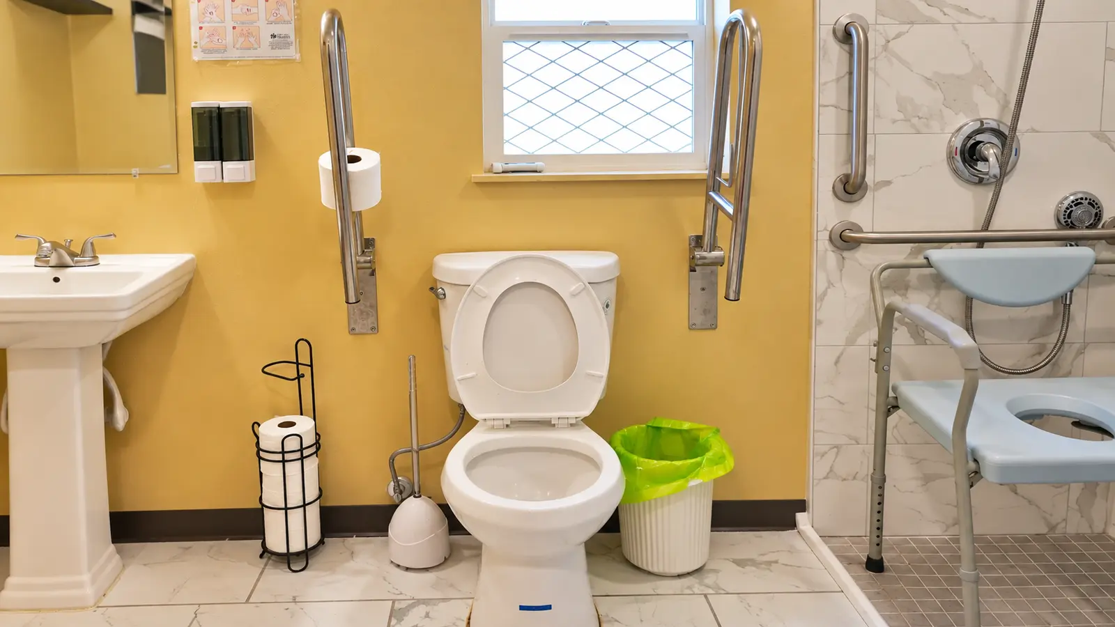 A bathroom at Prime Adult Family Home with fold-down grab bars on both sides of the toilet
