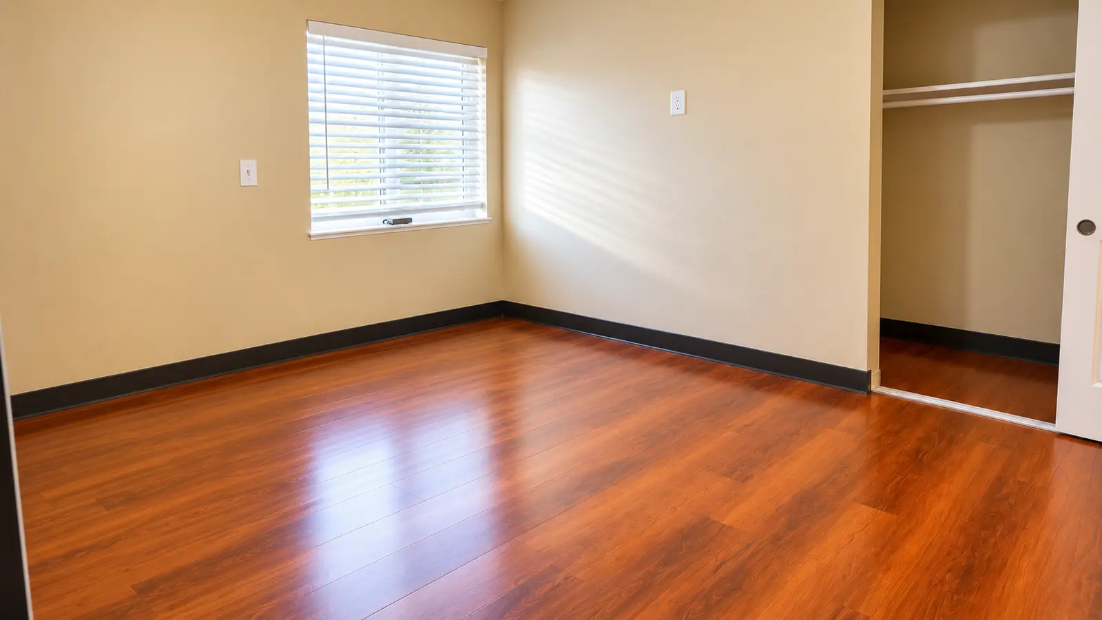 An unfurnished bedroom at Prime Adult Family Home with a window, a closet, and wood flooring