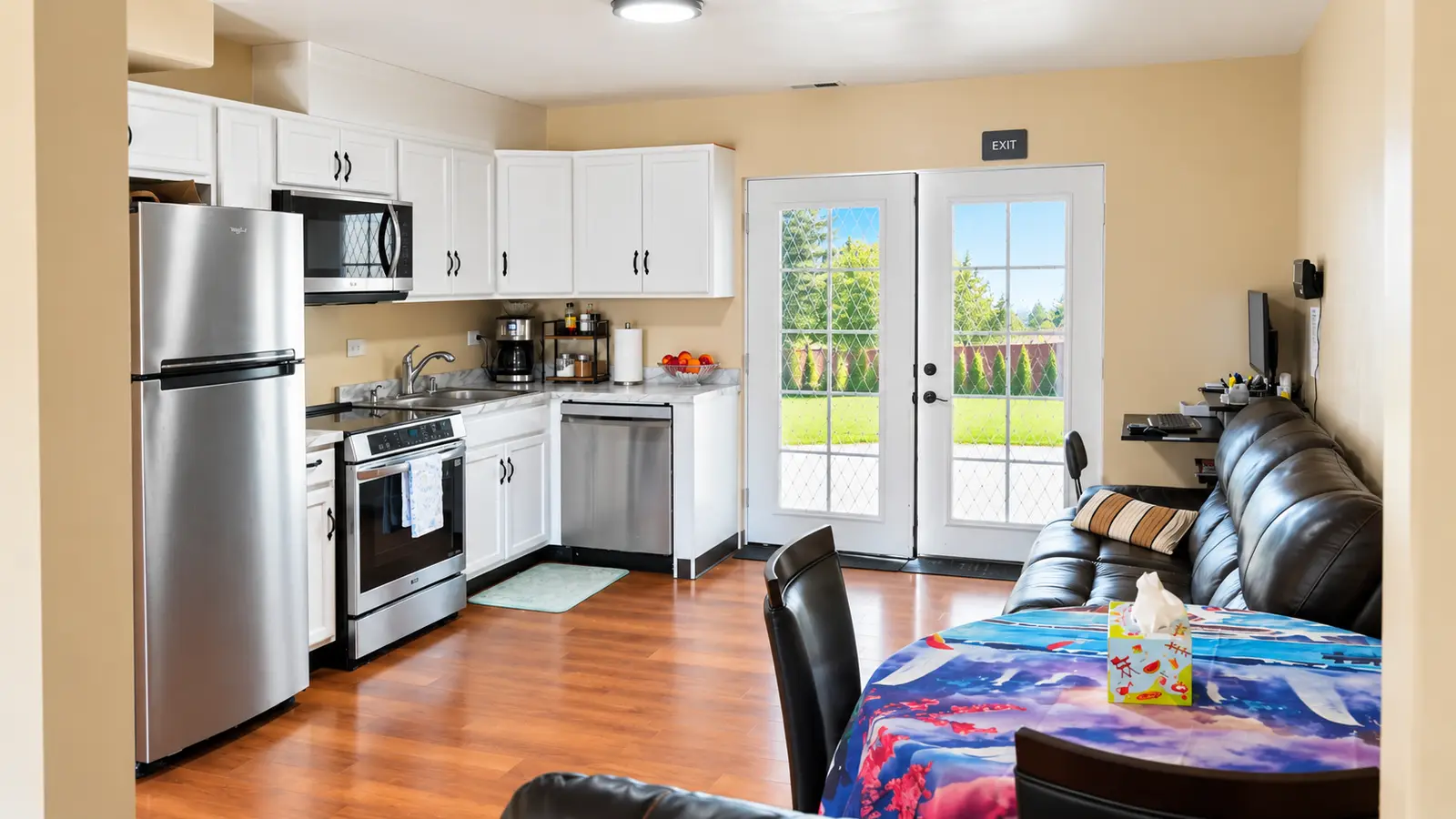 The kitchen at Prime Adult Family Home opening onto the dining table, with glass doors to the back garden