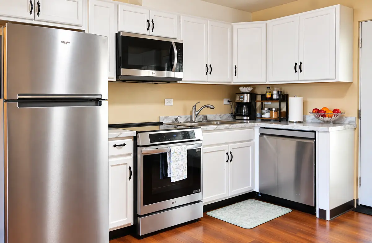 The kitchen at Prime Adult Family Home with a full-size range, refrigerator, dishwasher, and white cabinets